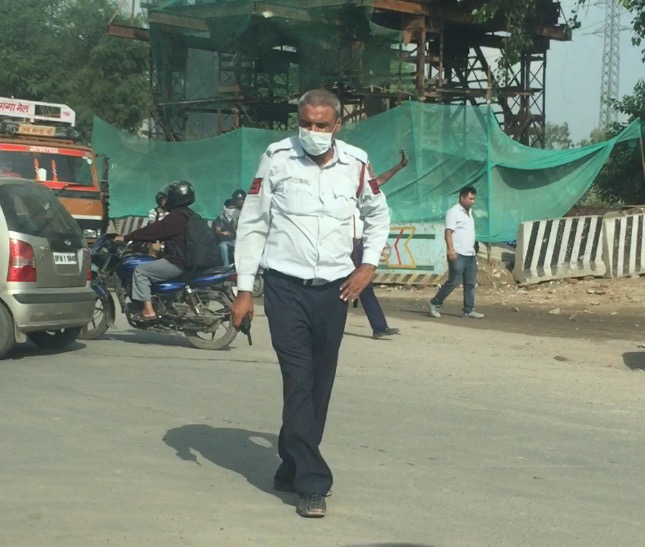 A TRAFFIC POLICEMAN WITH A FACE MASK AT A DELHI CROSSING. 